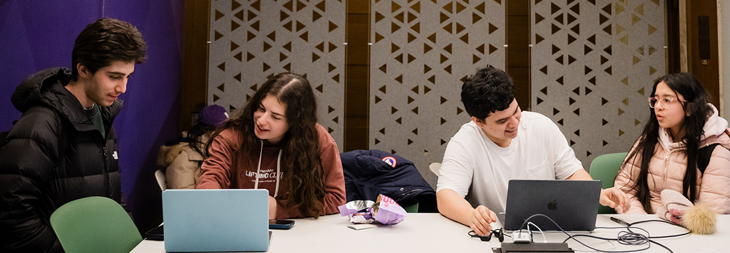 Four students collaborating on laptops