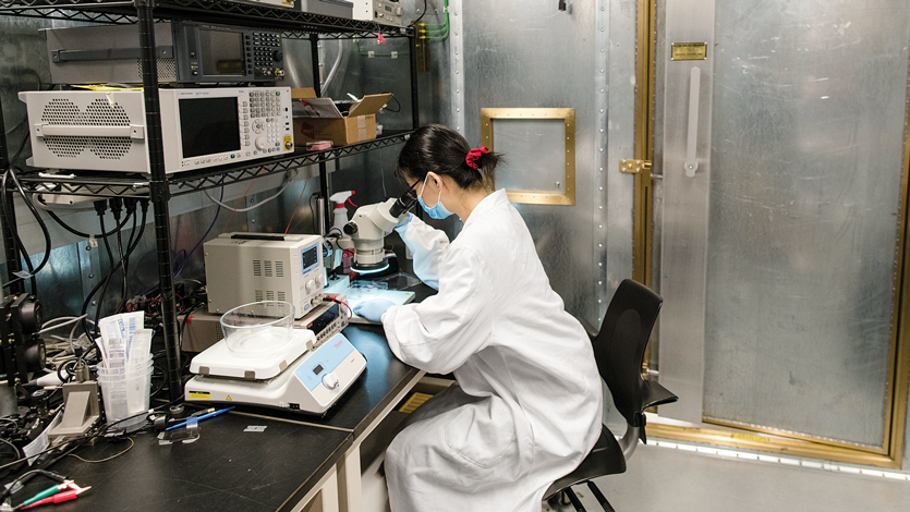 A students uses a microscope in the Faraday Cage